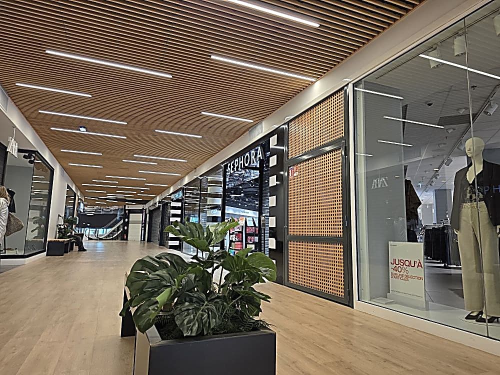 Galerie commerciale au plafond bois acoustique Ardemo, lattes de bois clair