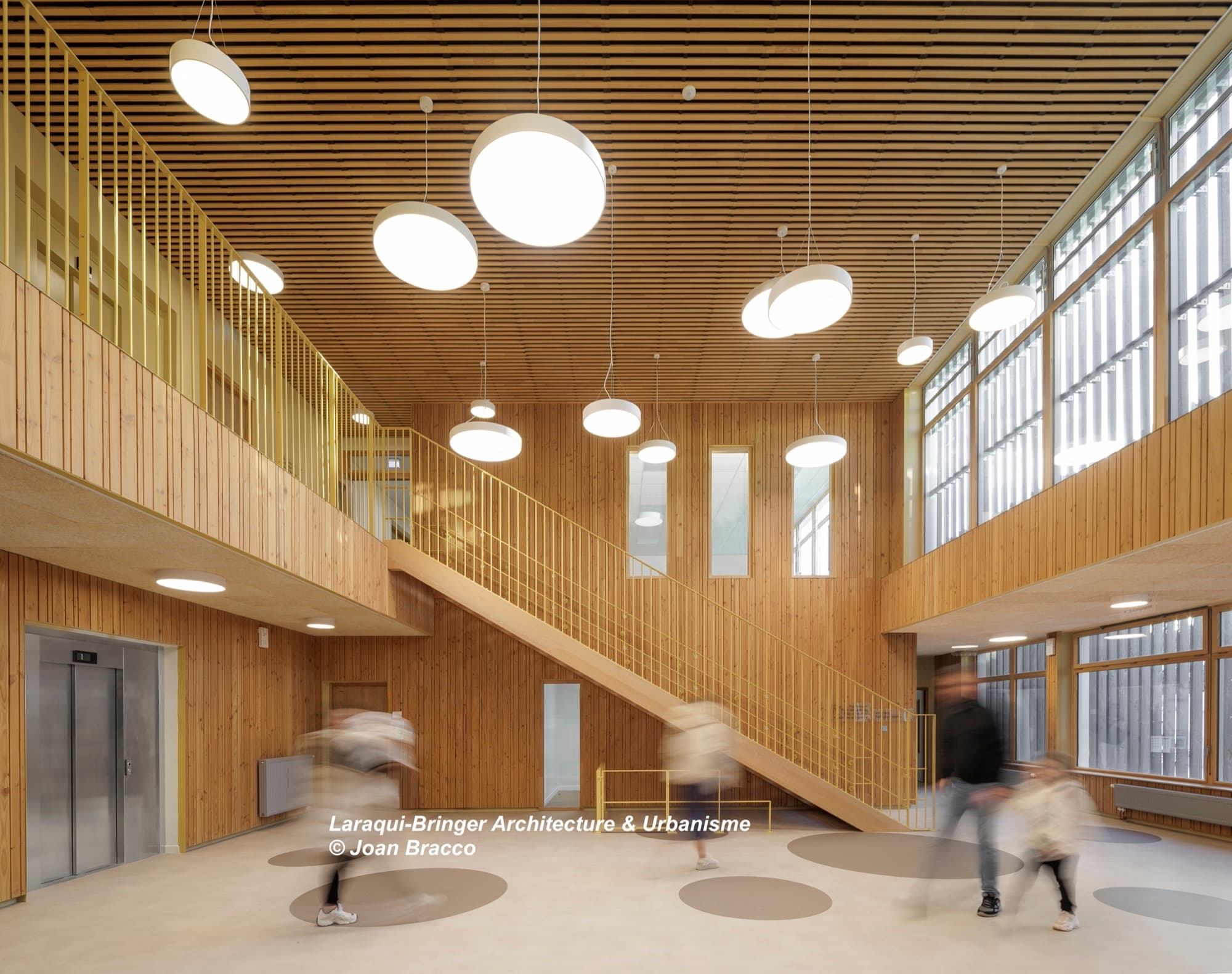 Hall à double hauteur de l'école maternelle Robespierre à Bobigny, plafond bois acoustique Ardemo Ecogrid pin